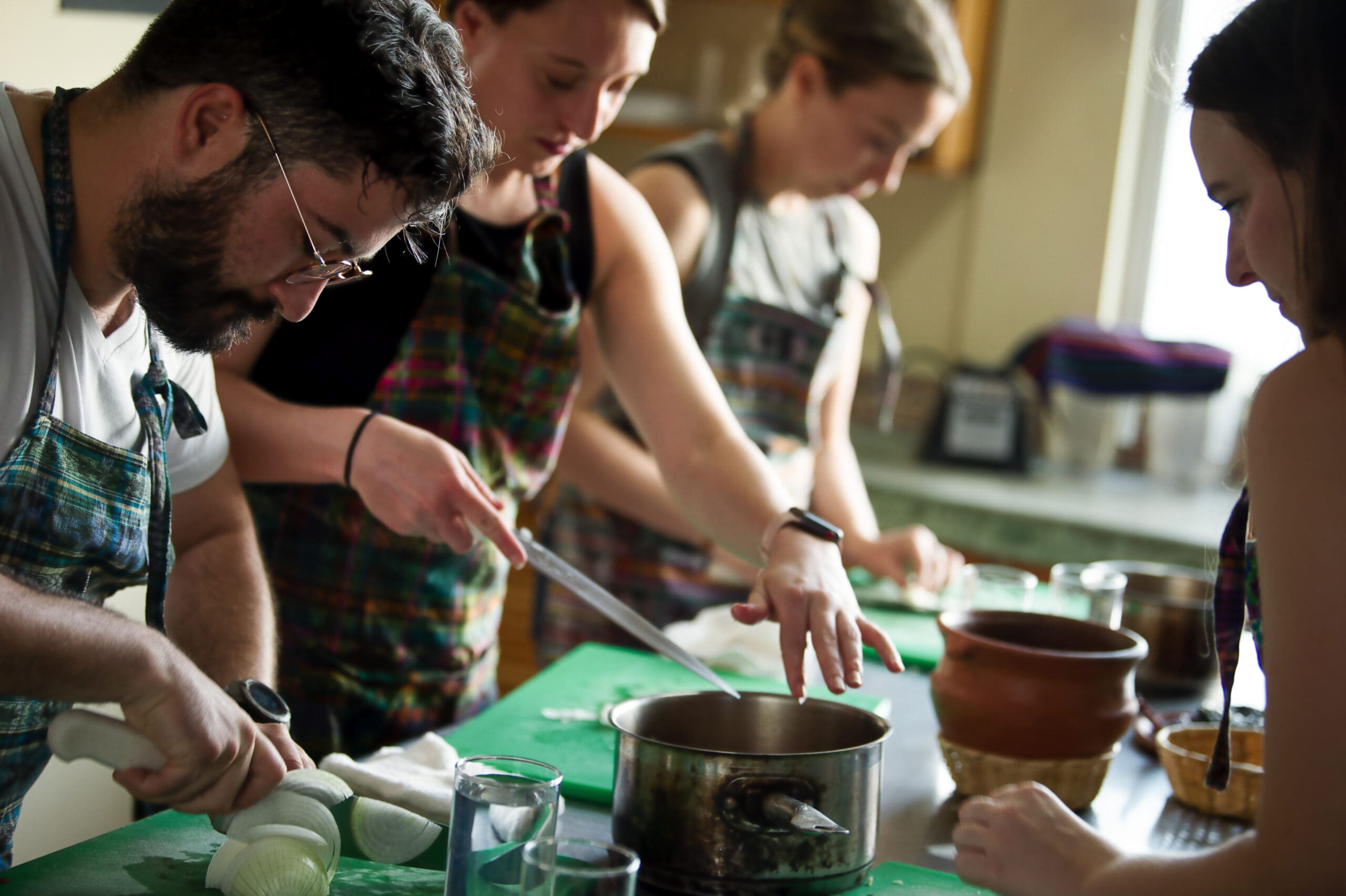 Group gathered in the kitchen chopping vegetables.