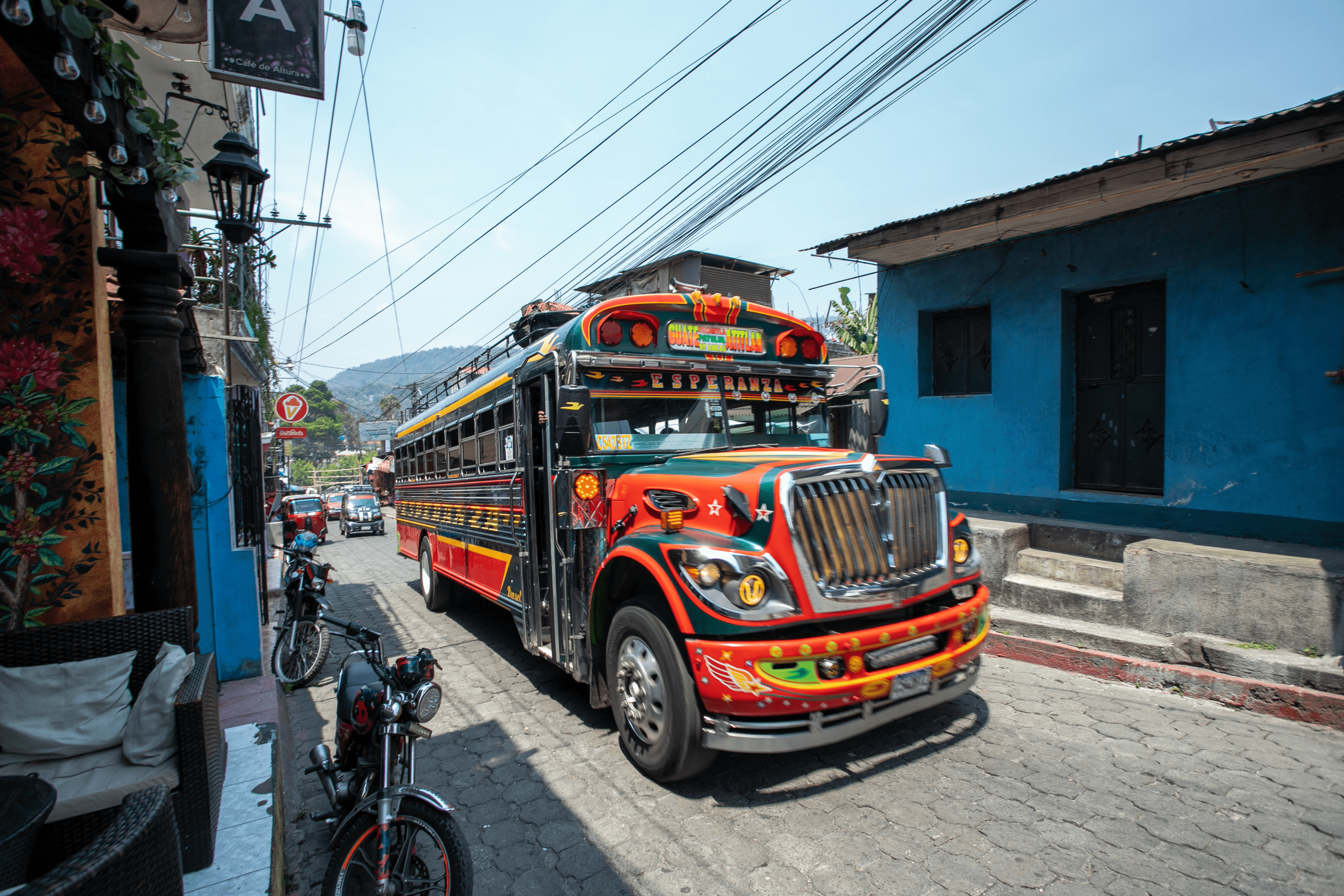 Brightly hand-painted american school bus driving through cobbled streets.