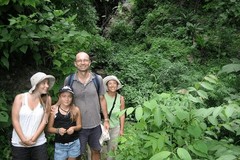 Mother, father and two daughters surrounded by green leaves.
