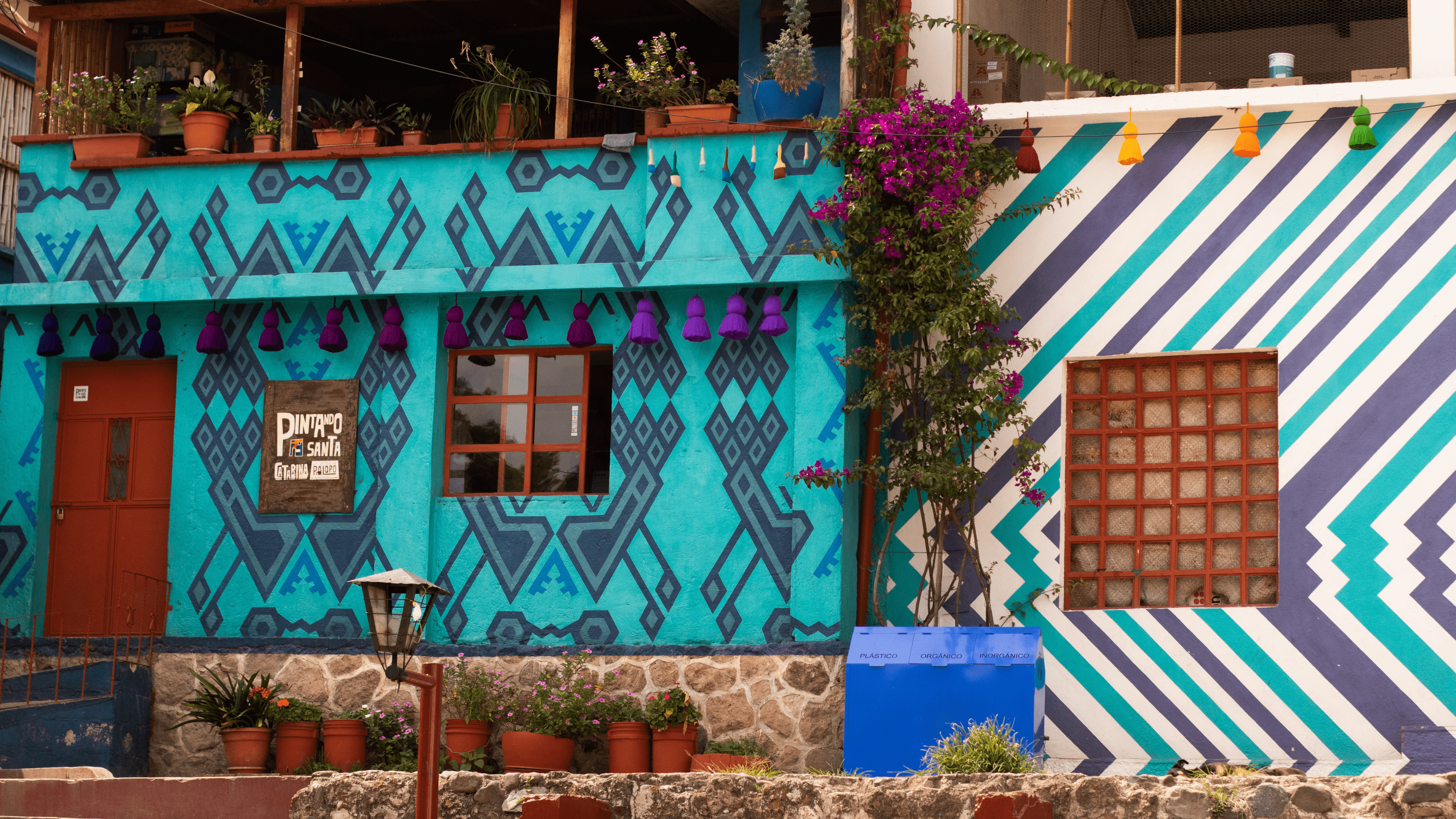 Two houses painted turqoise and purple geometric patterns.