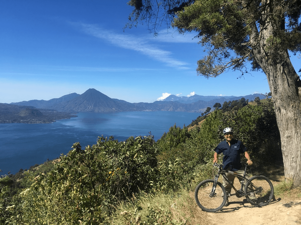 Cyclist poses proudly in front of Lake Atitlan from 3,000m above.
