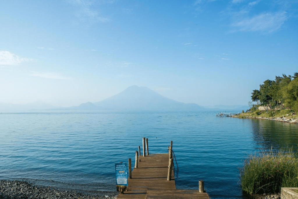 Wooden boardwalk out onto the lake with volcano in the distant background.